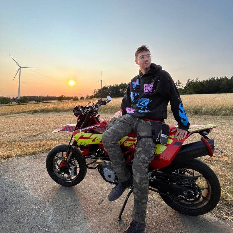 Supermoto im atemberaubenden Sonnenuntergang. Janik Rabenstein sitzt seitlich auf dem Motorrad.